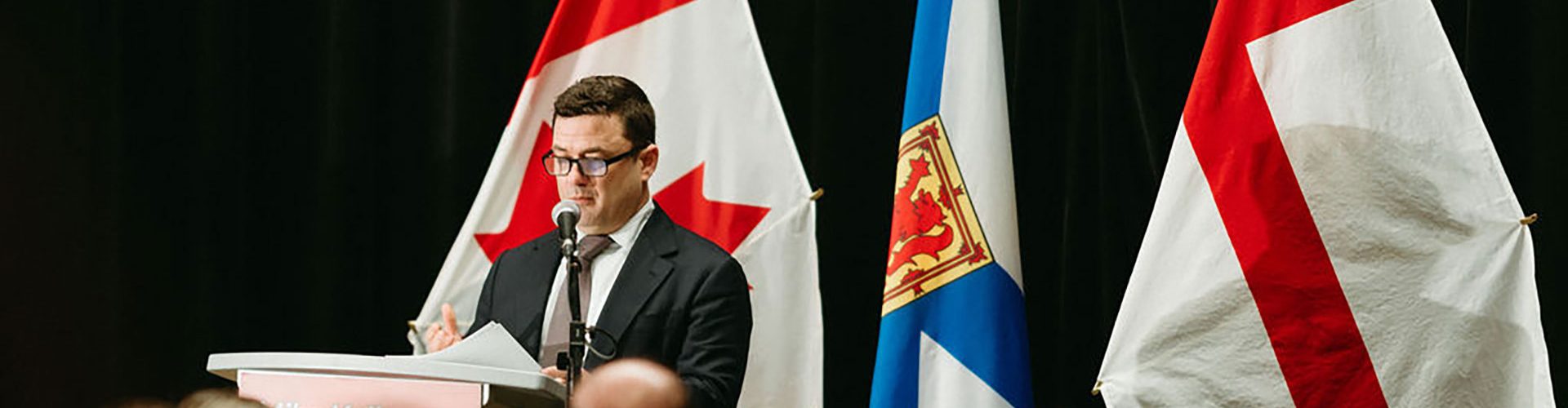 Trent Vichie speaking at a podium in front of a group of people